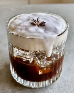 Smartphone photo of Lavender Cold Foam cascading into dark espresso with morning light and condensation.
