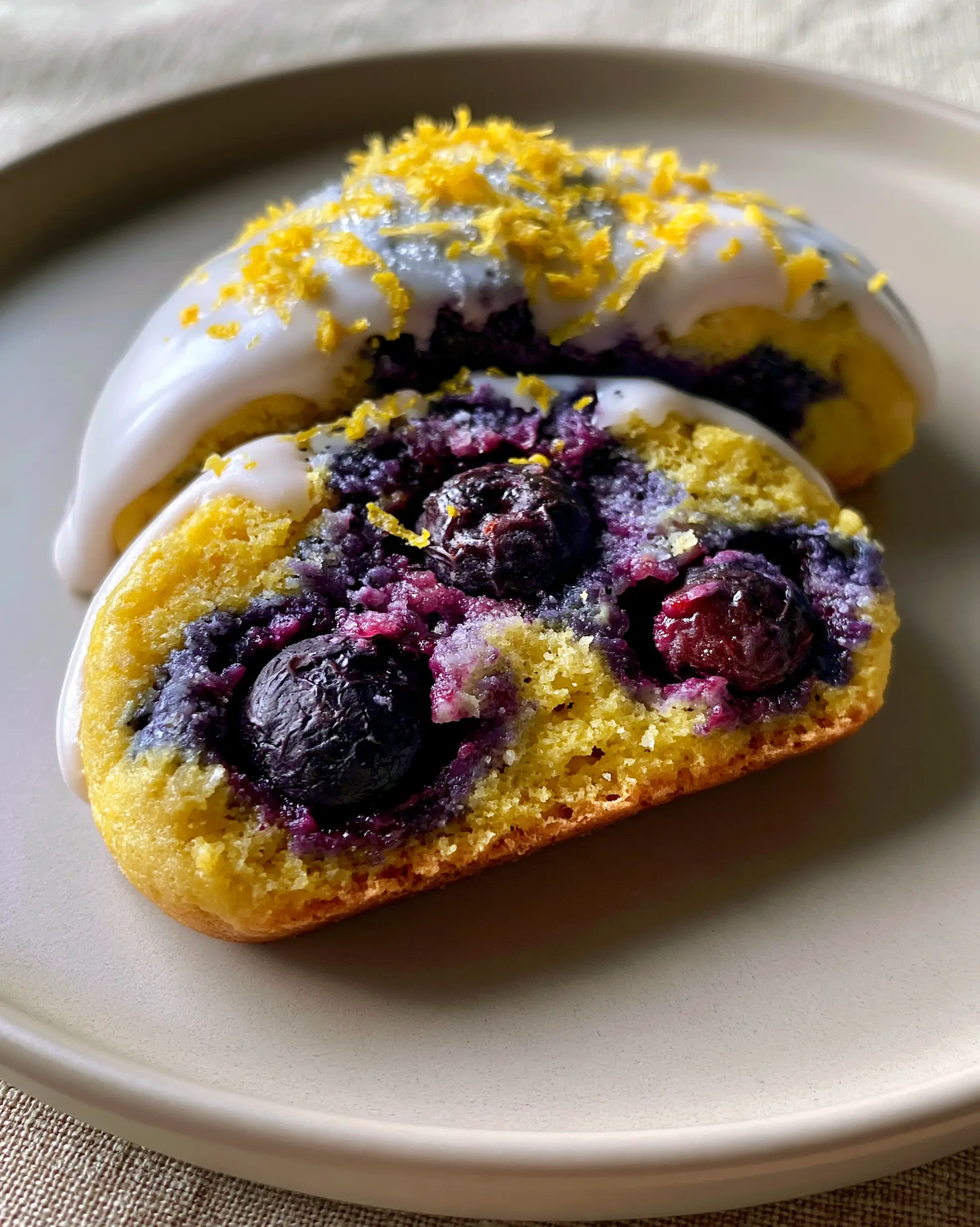 A single lemon blueberry cookie broken in half showing the soft golden interior and jammy blueberries. (lemon blueberry cookies)