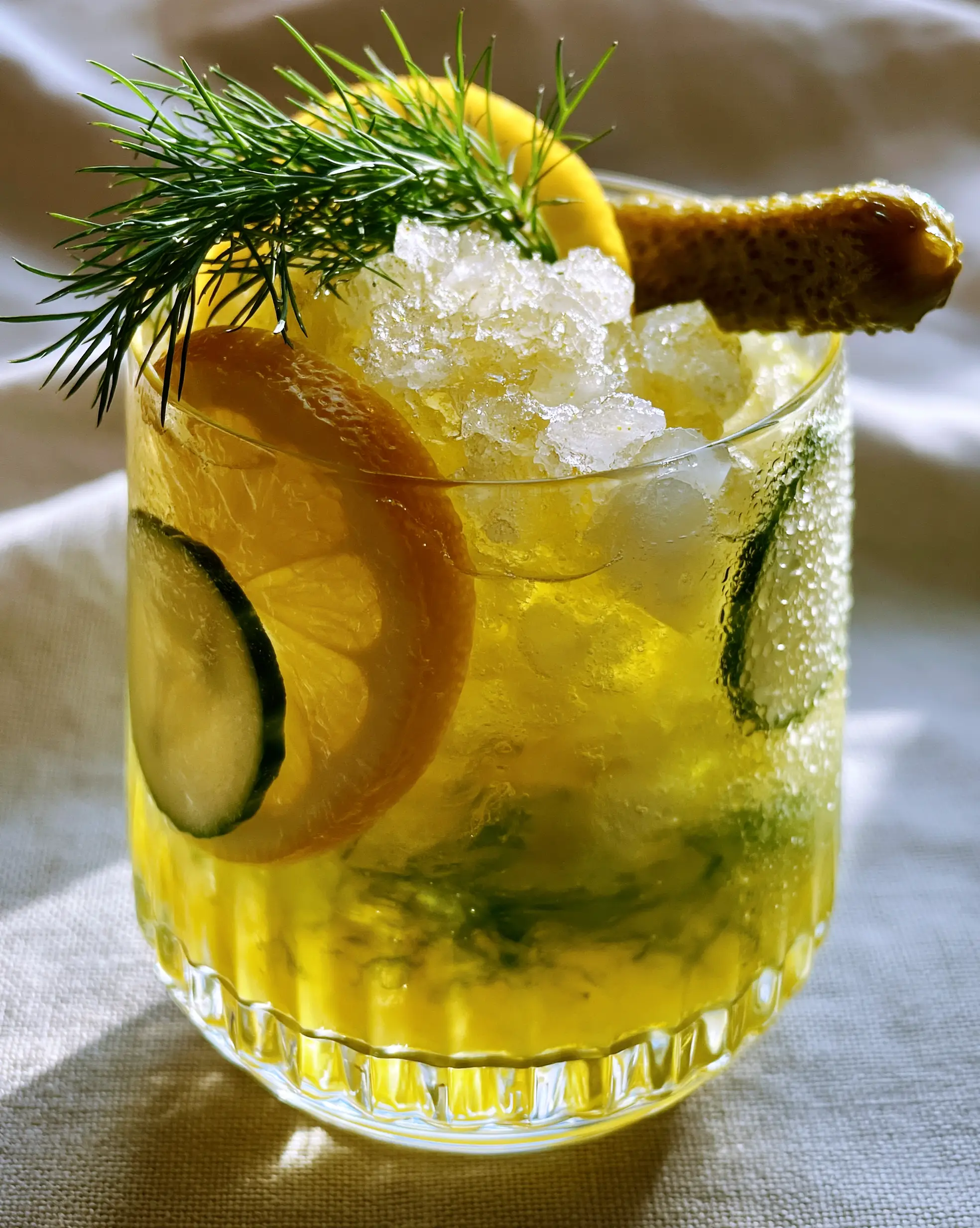 Eye-level close-up of Pickle Lemonade with glistening crushed ice and a green pickle juice swirl in a modern ribbed glass.
